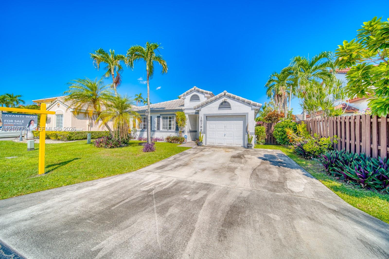 Single-story exterior featuring a concrete tile roof, attached one-car garage, concrete driveway, and mature landscaping