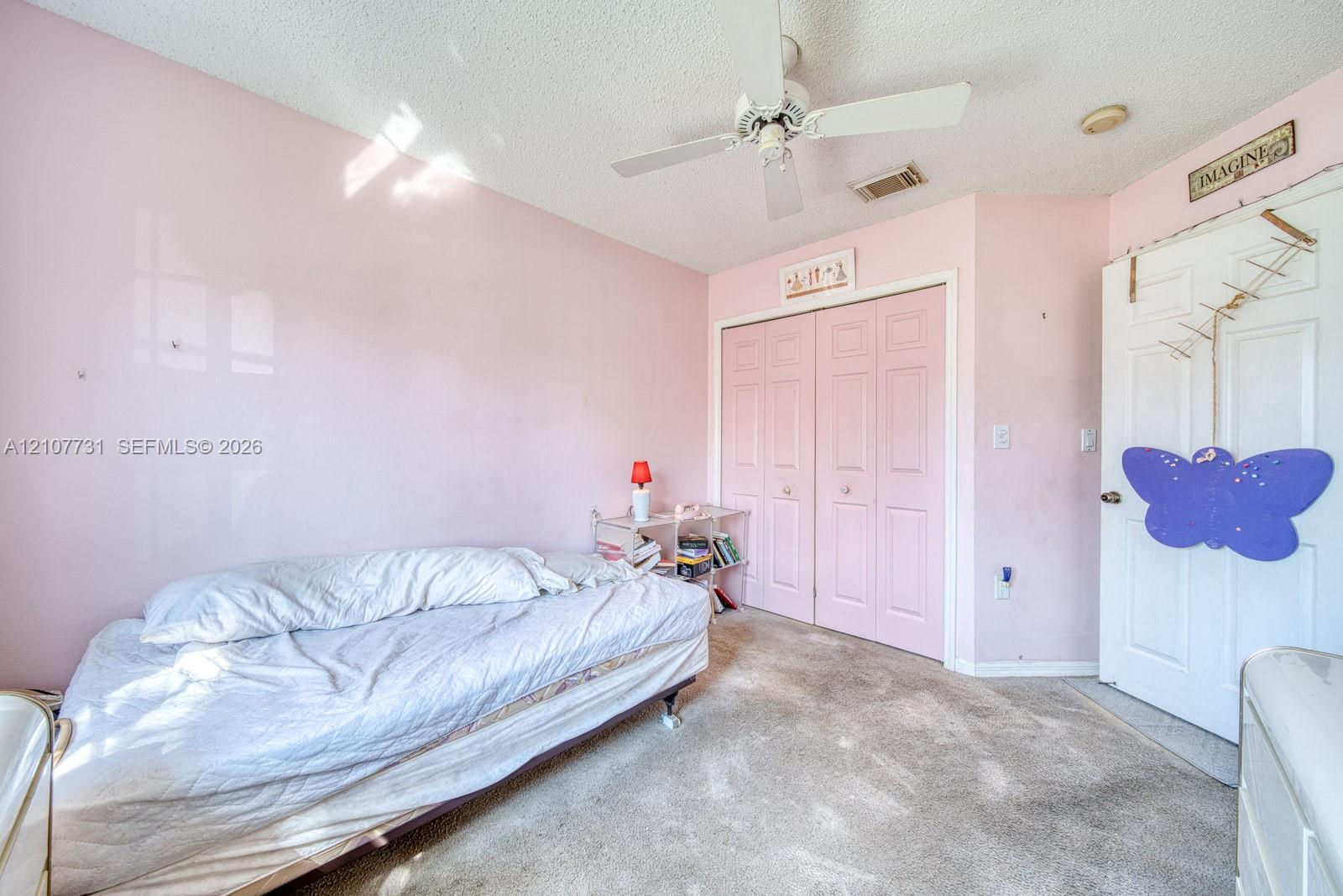 Room featuring neutral-toned carpeting, dual-panel closet doors, and a ceiling-mounted fan with integrated lighting