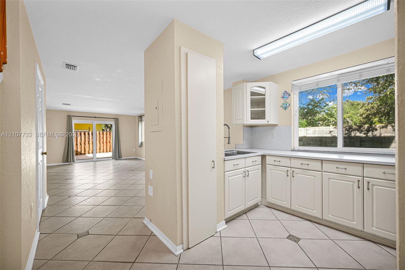 Kitchen featuring white cabinetry, solid surface countertops, and tile flooring with decorative inserts