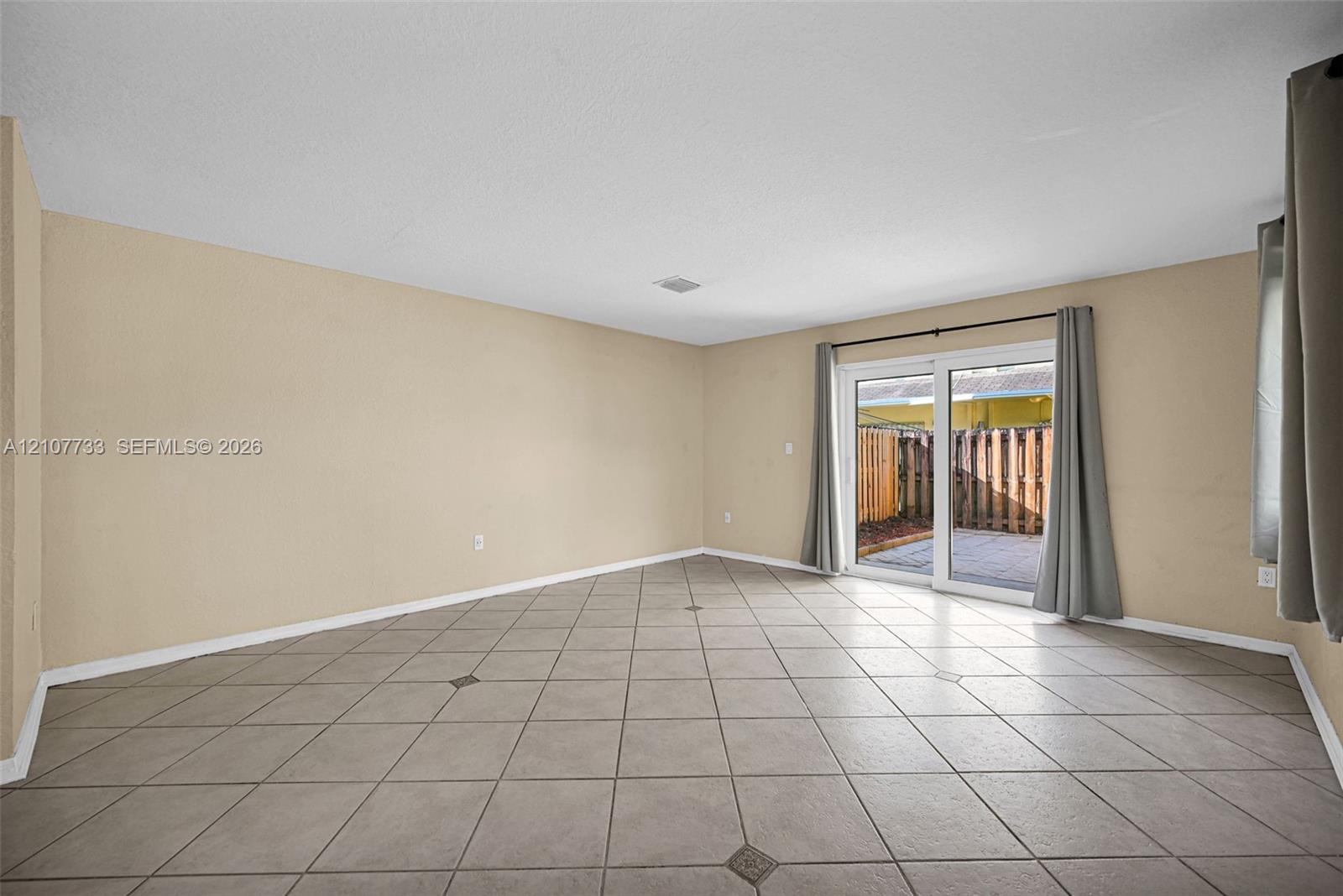 Interior space featuring diagonal ceramic tile flooring and sliding glass doors leading to a paved outdoor area
