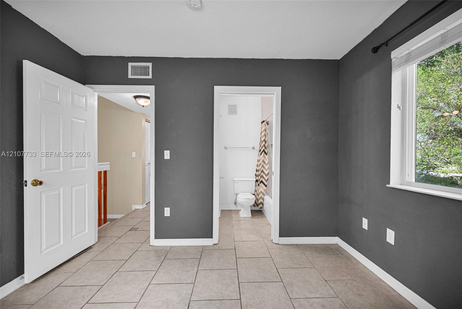 Room featuring tile flooring, painted charcoal-toned walls, and a multi-pane window