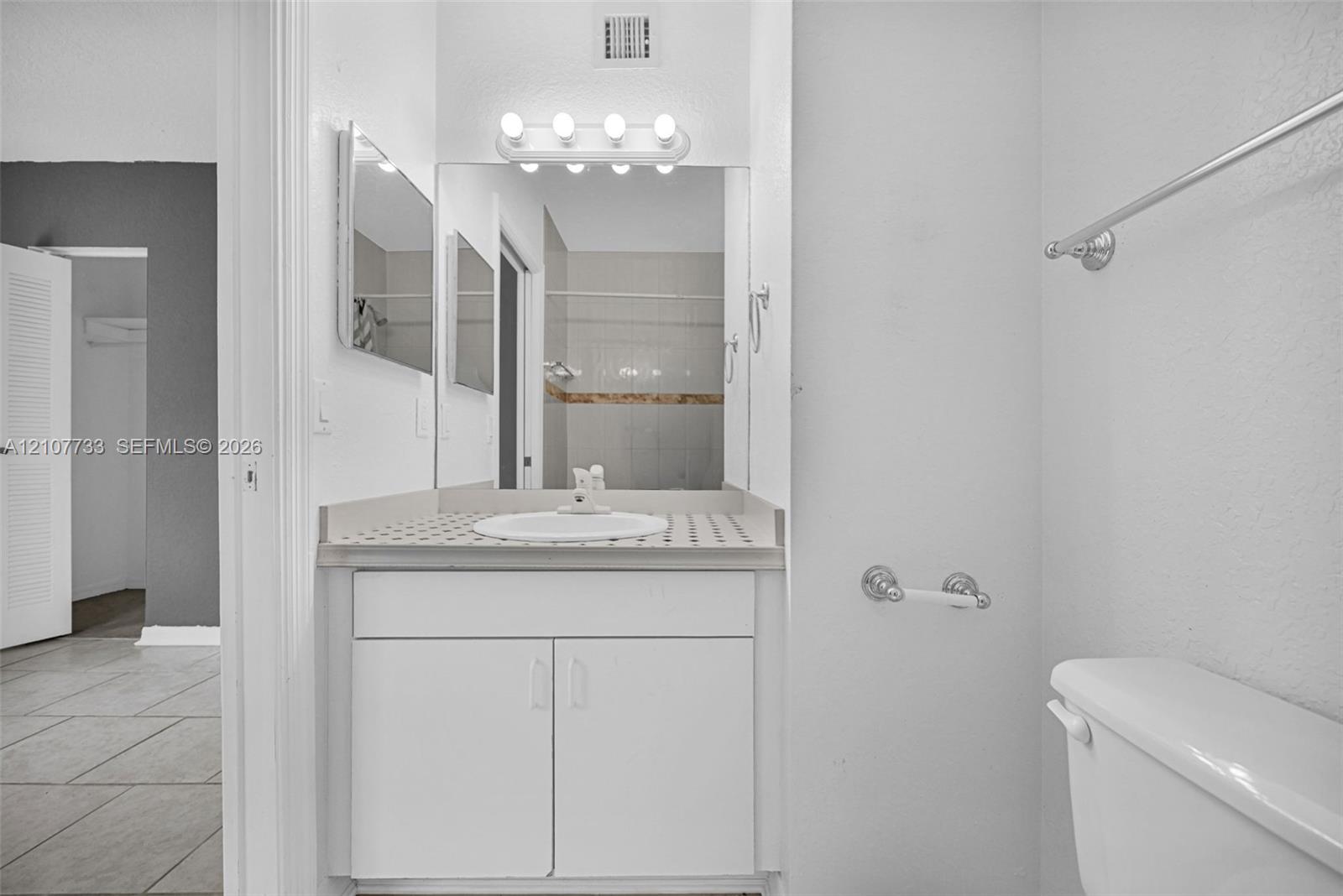 Bathroom featuring a vanity with a circular drop-in sink, tiled countertop, five-light wall-mounted vanity fixture, and large square mirror