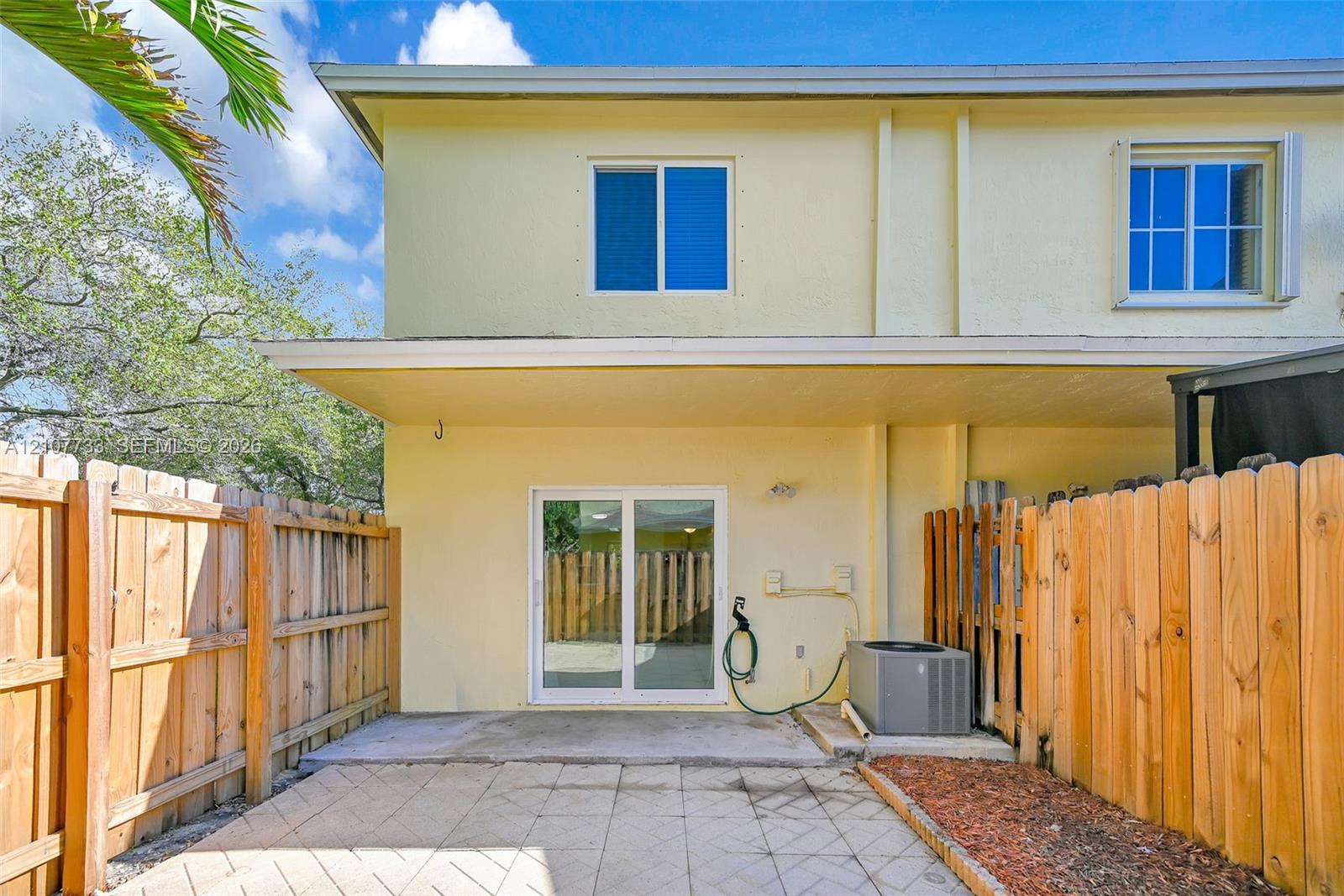 Rear exterior featuring a concrete patio, sliding glass doors, and a wood privacy fence