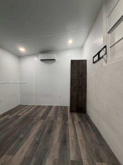 Interior space featuring wood-finish flooring, recessed lighting, a wall-mounted ductless climate control unit, and floor-to-ceiling built-in cabinetry
