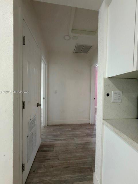 Interior hallway featuring wood-finish flooring, white cabinetry, solid-surface countertops, and recessed lighting