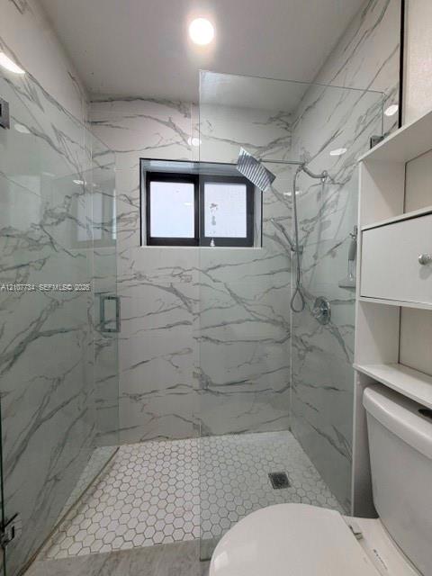 Walk-in shower featuring large-format patterned wall tile, hexagonal floor tile, a glass enclosure, and a modern rain-style shower head