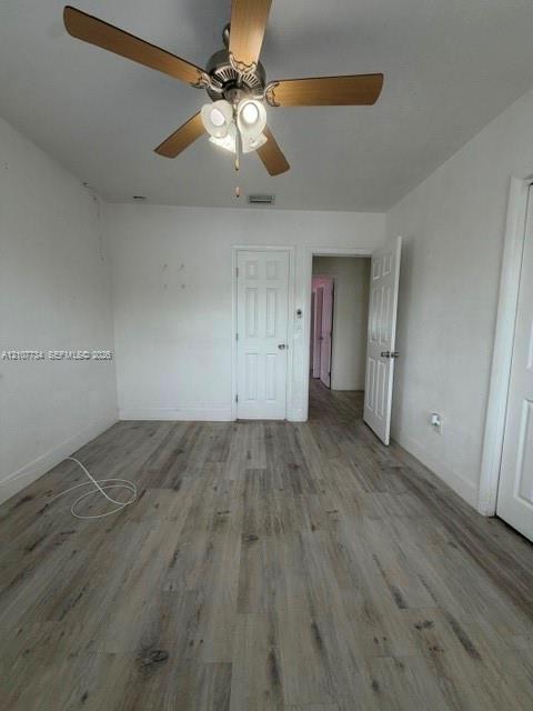Wood-finish flooring, ceiling fan with integrated lighting, and multi-panel interior doors