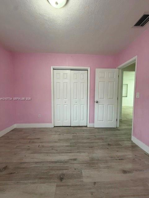 Room featuring wood-finish flooring, dual-panel closet doors, and a paneled entry door
