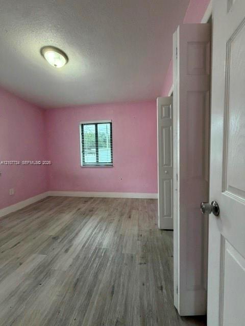 Room featuring wood-finish flooring, a single window, a ceiling-mounted light fixture, and a bi-fold closet door