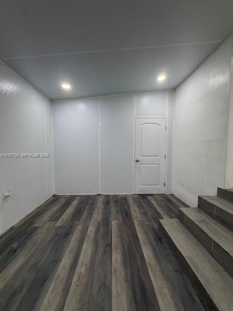 Interior space featuring wood-finish flooring, recessed lighting, smooth-finish wall panels, and a single-panel arched door