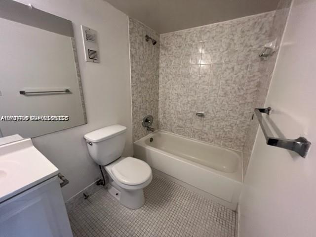 Bathroom featuring a vanity with integrated sink, porcelain bathtub, metallic finish fixtures, wall-mounted mirror, and tiled flooring