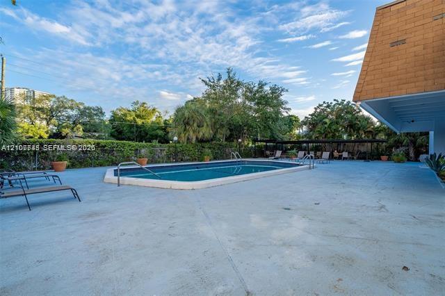 Outdoor swimming pool featuring a concrete deck, metal pool railings, and surrounding greenery
