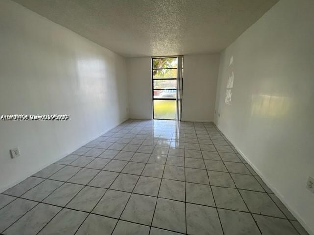 Interior space featuring neutral wall finishes, light-toned ceramic tile flooring, and a floor-to-ceiling multi-pane window