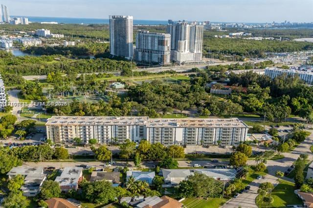Aerial perspective of a multi-story residential building featuring private balconies, expansive surface parking, and mature perimeter landscaping