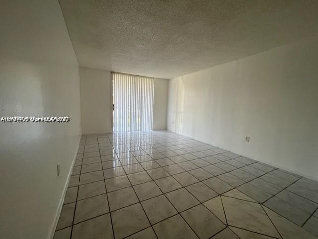 Open-concept interior featuring neutral ceramic tile flooring and floor-to-ceiling vertical blinds covering a sliding glass door
