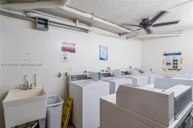 Laundry facility featuring multiple top-load washing machines, a ceiling fan, and a deep basin utility sink