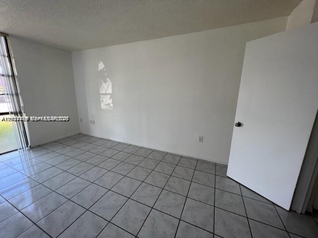 Room featuring large-format ceramic tile flooring and floor-to-ceiling glass sliding doors