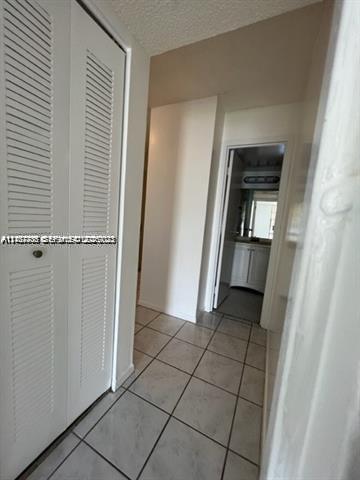 Neutral-toned ceramic tile flooring, floor-to-ceiling closet with louvered double doors, and white interior doors