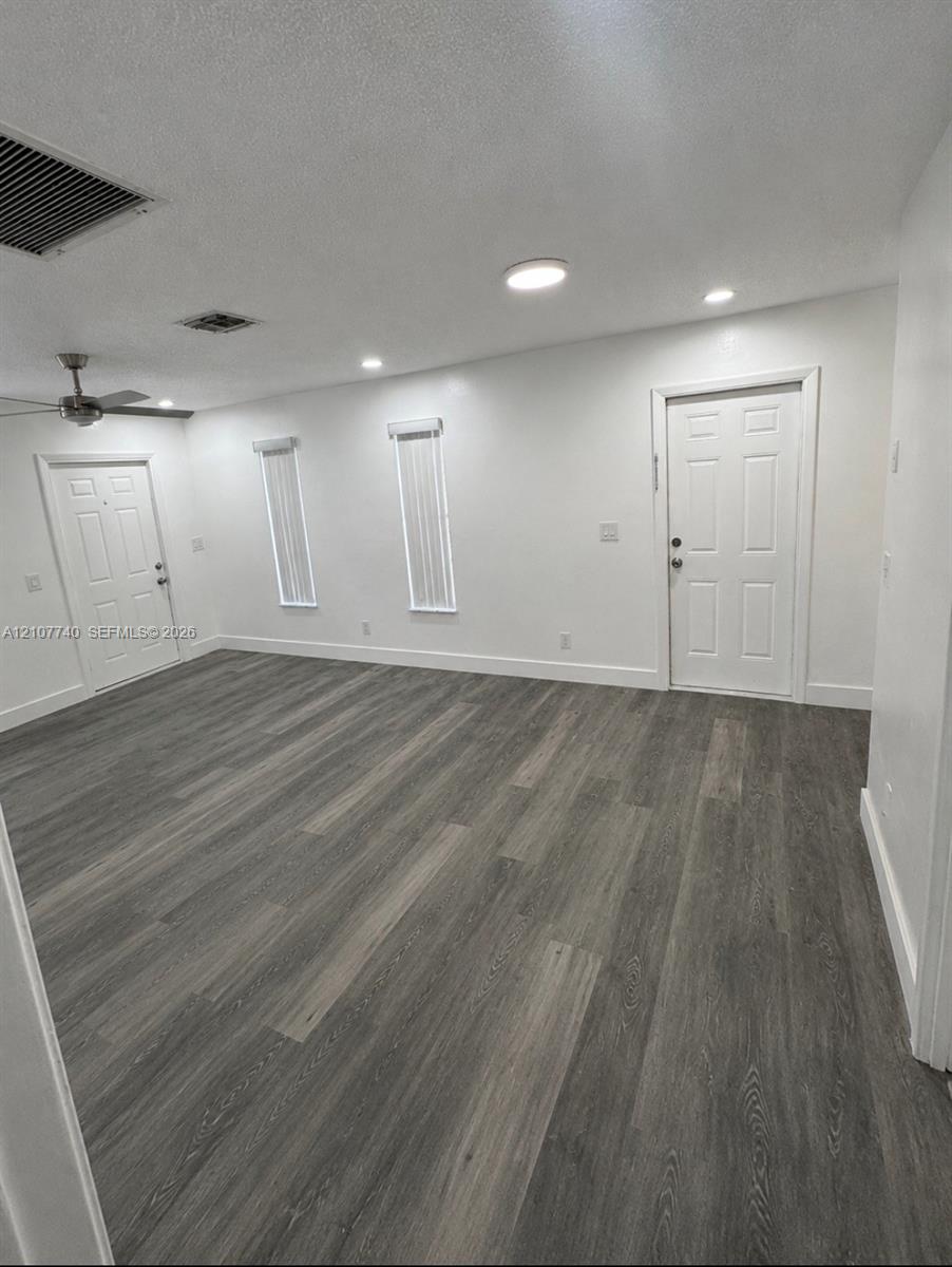 Open floor plan featuring wood-finish flooring, recessed lighting, a ceiling fan, and two multi-panel entry doors