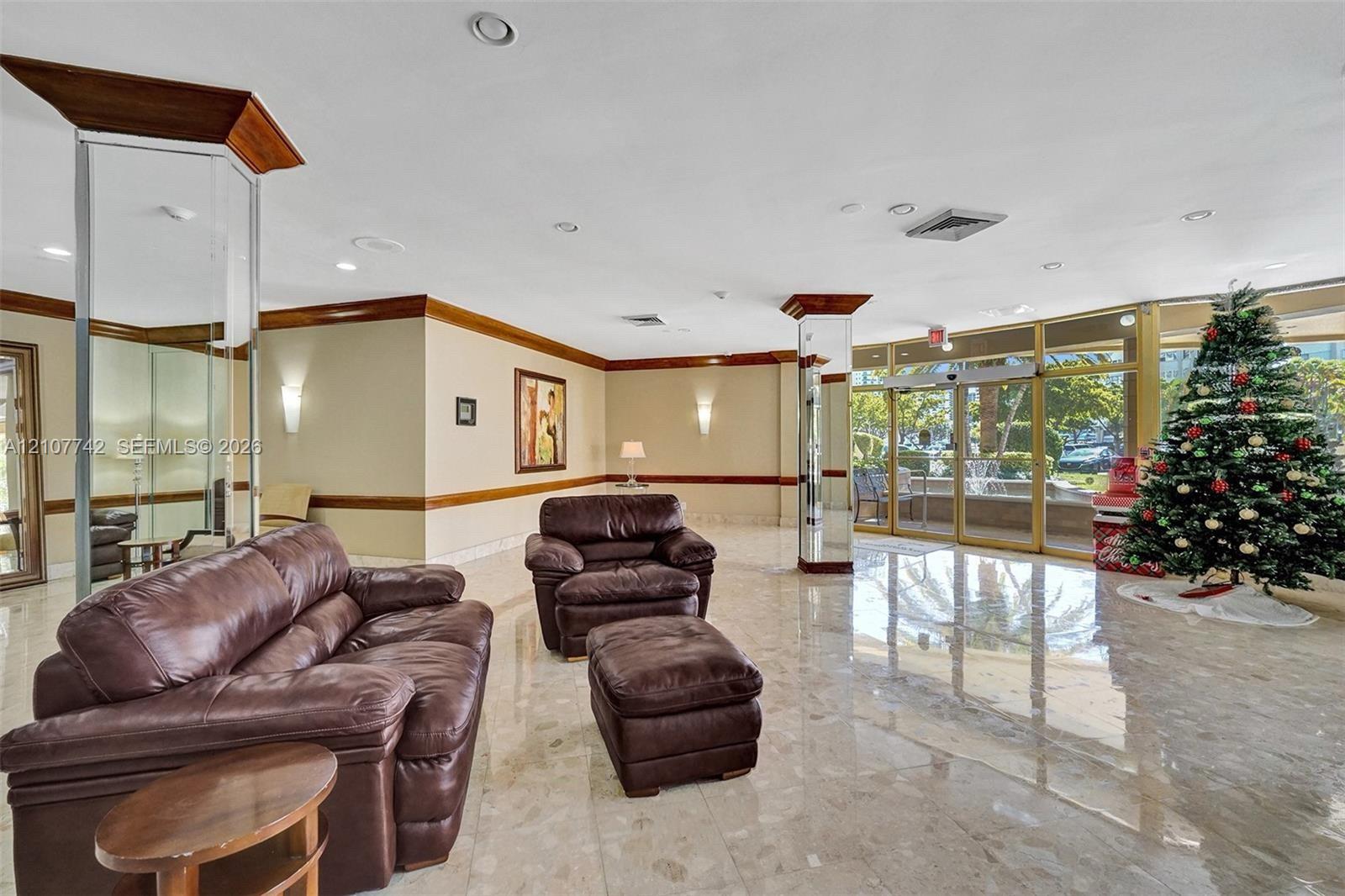 Common area lobby featuring polished stone flooring, mirrored structural columns, crown molding, and floor-to-ceiling glass panel walls