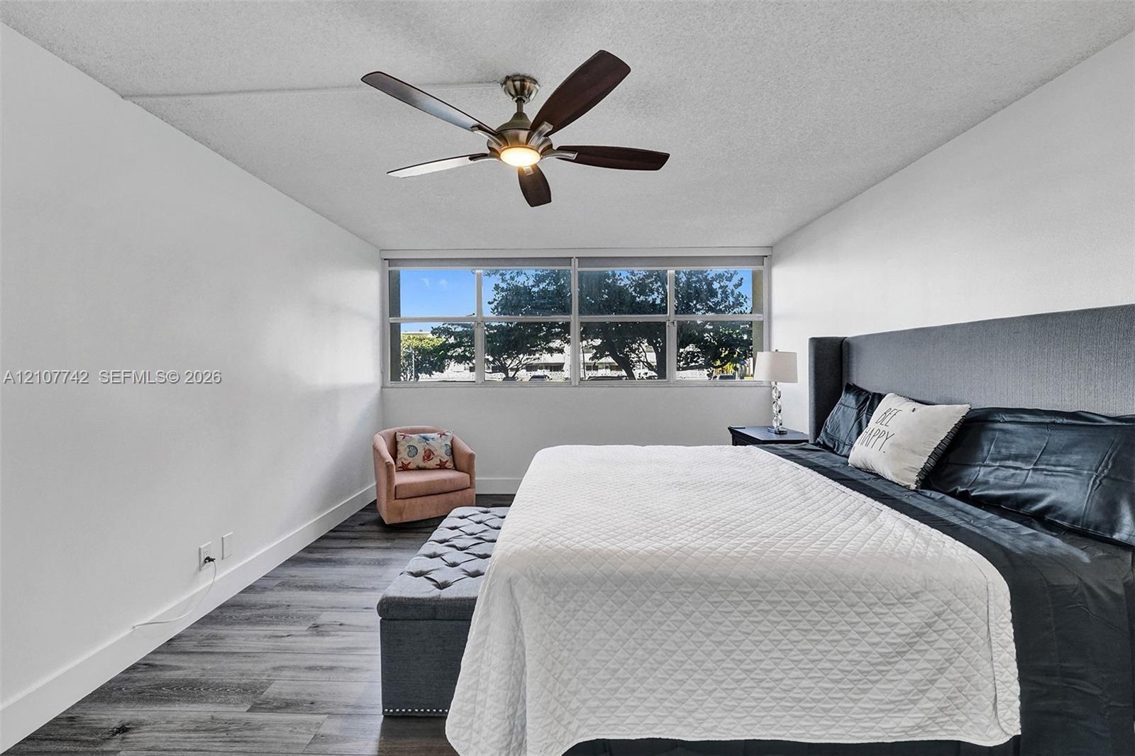 Wood-finish flooring, multi-pane picture windows, and a ceiling fan with integrated lighting
