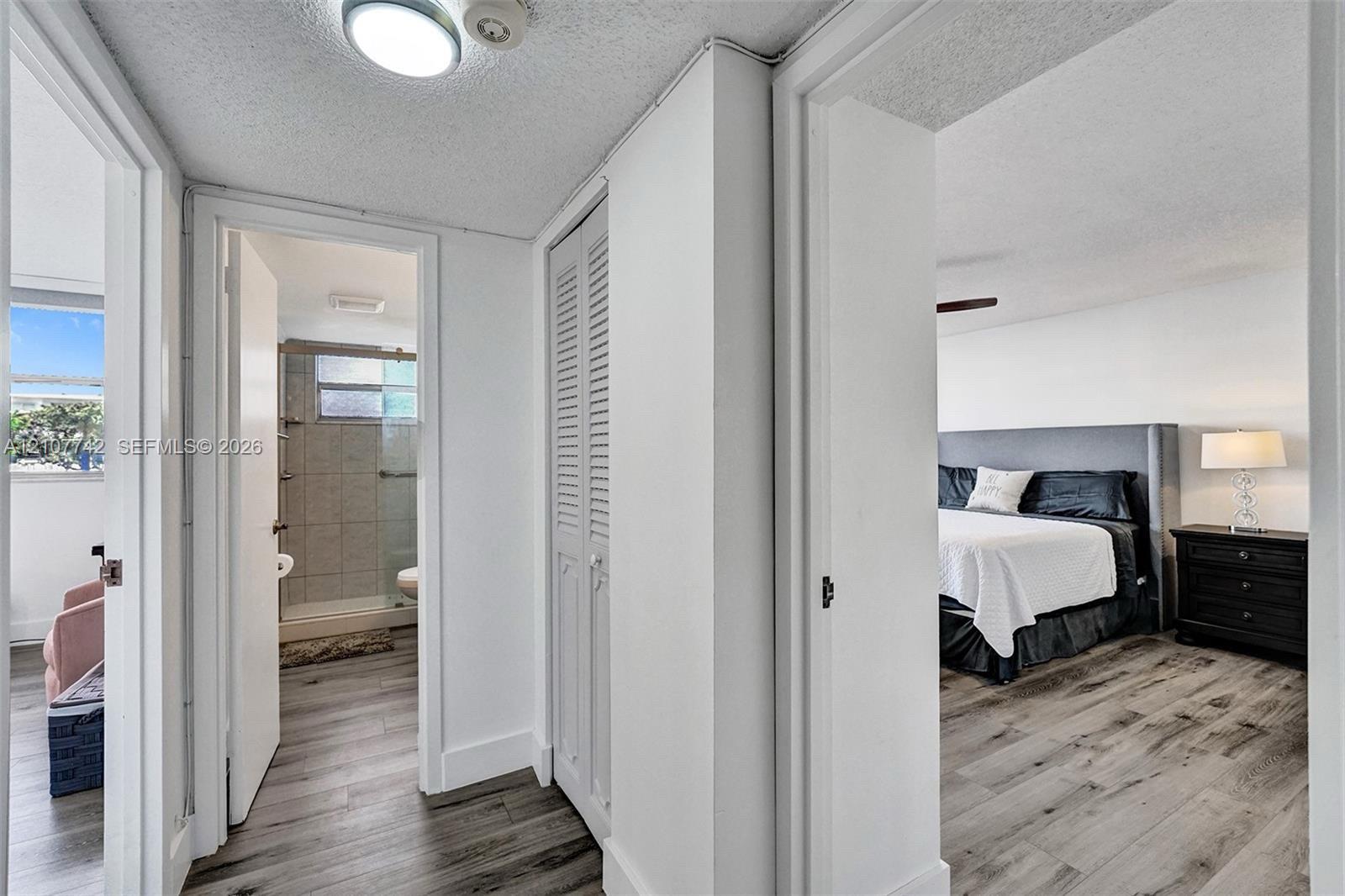 Interior hall featuring wood-finish flooring, ceiling-mounted lighting, and louvered bifold closet doors