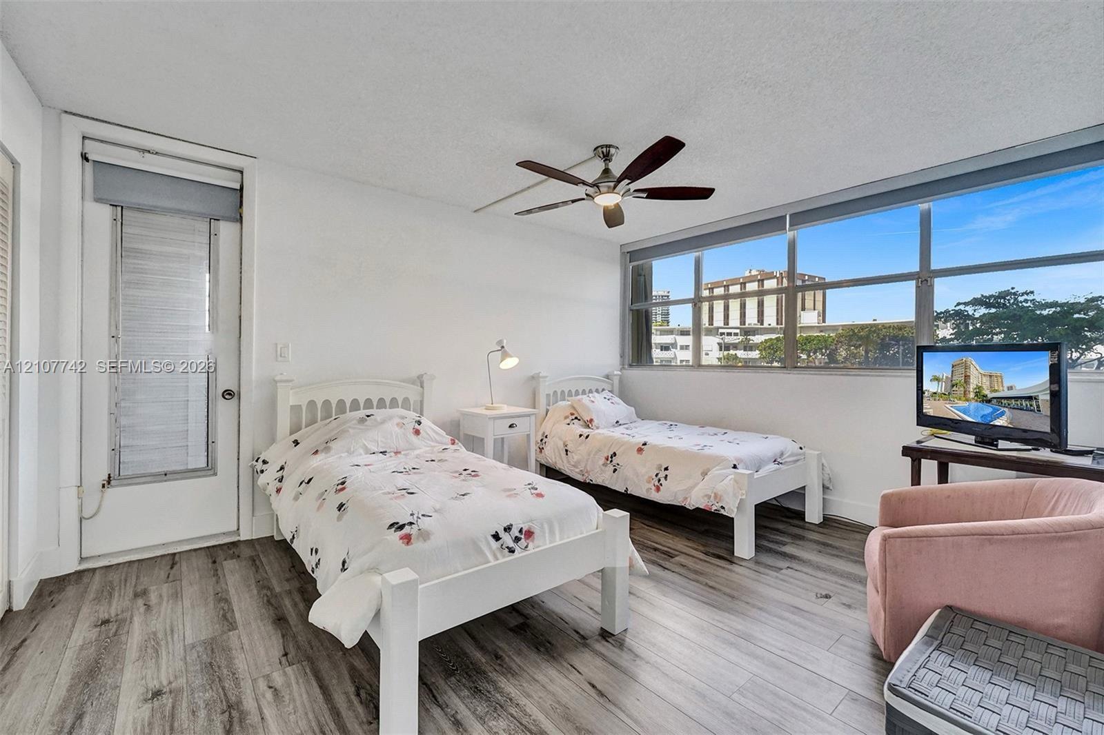Wood-finish flooring, floor-to-ceiling windows, and a ceiling fan with integrated lighting
