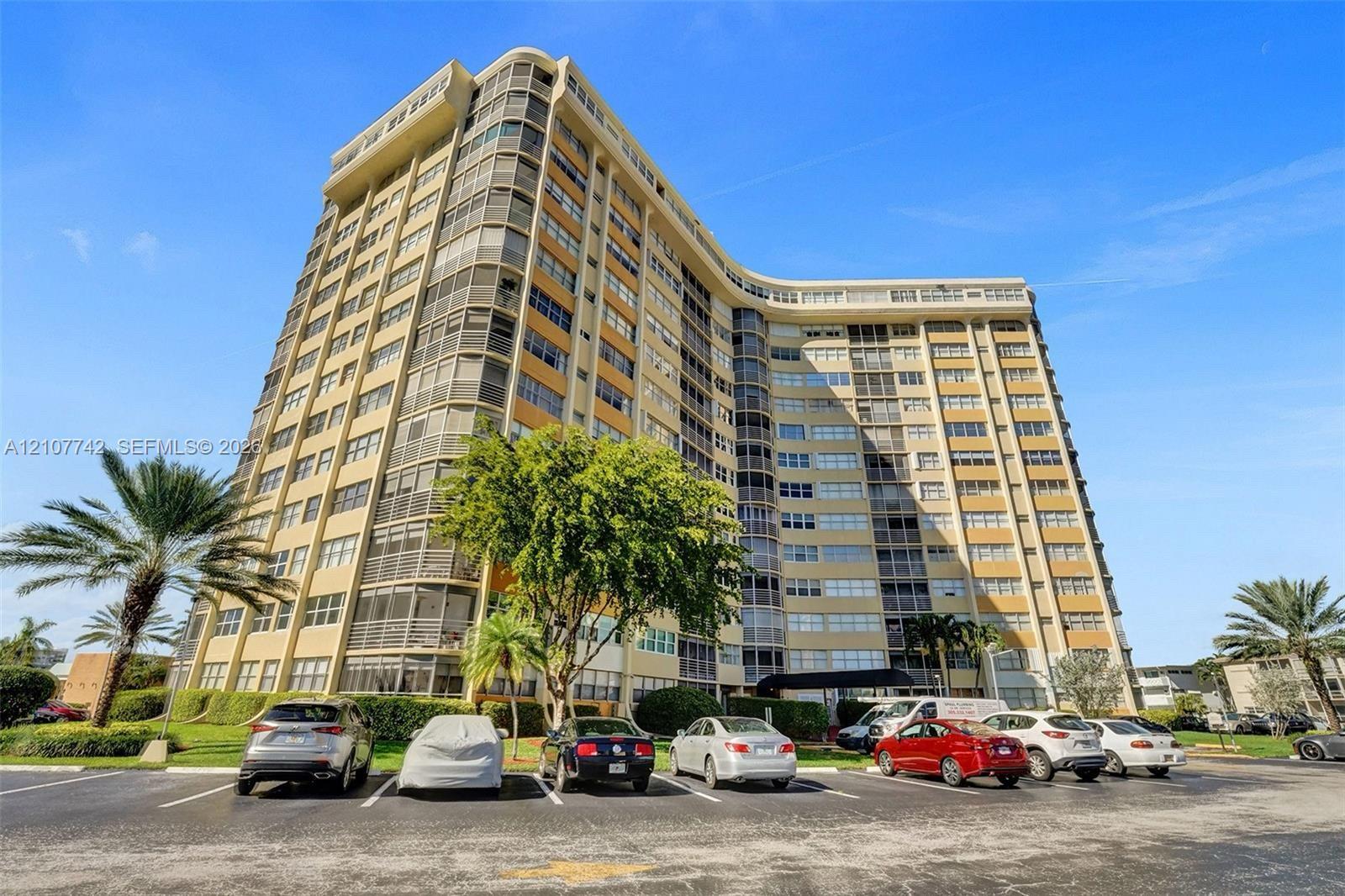 High-rise residential building featuring a curved architectural design, concrete facade, and private screened balconies