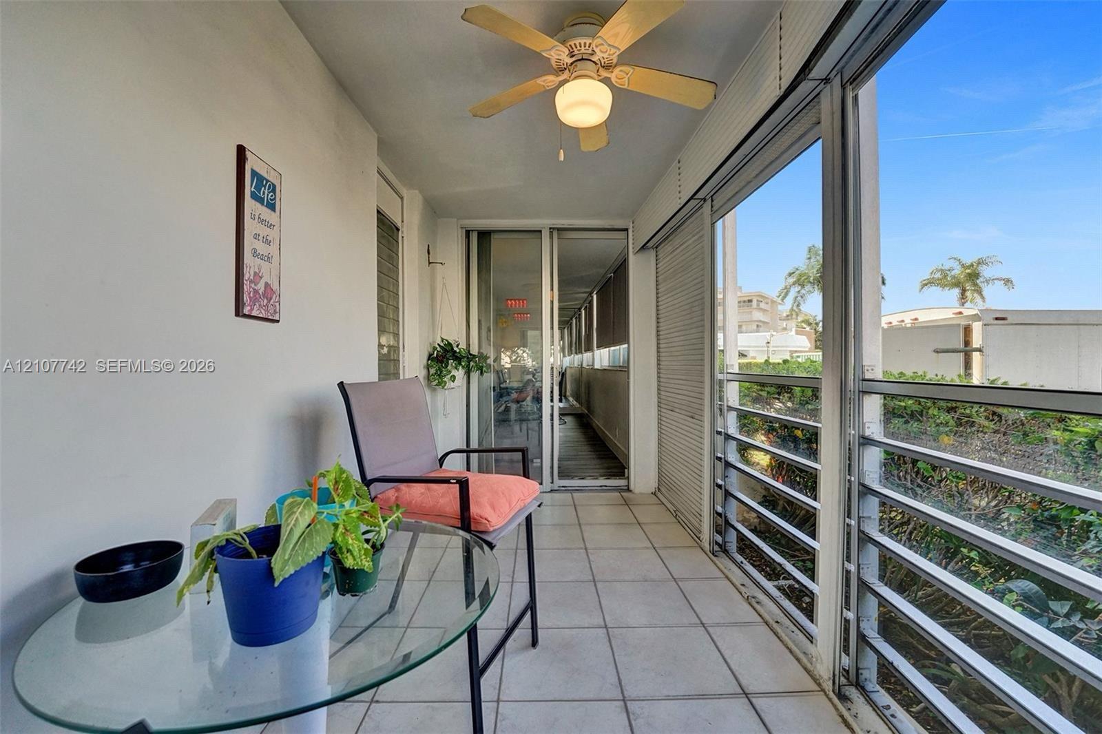 Enclosed lanai featuring large-format tile flooring, a mounted ceiling fan, metal-framed windows, and sliding glass entry doors