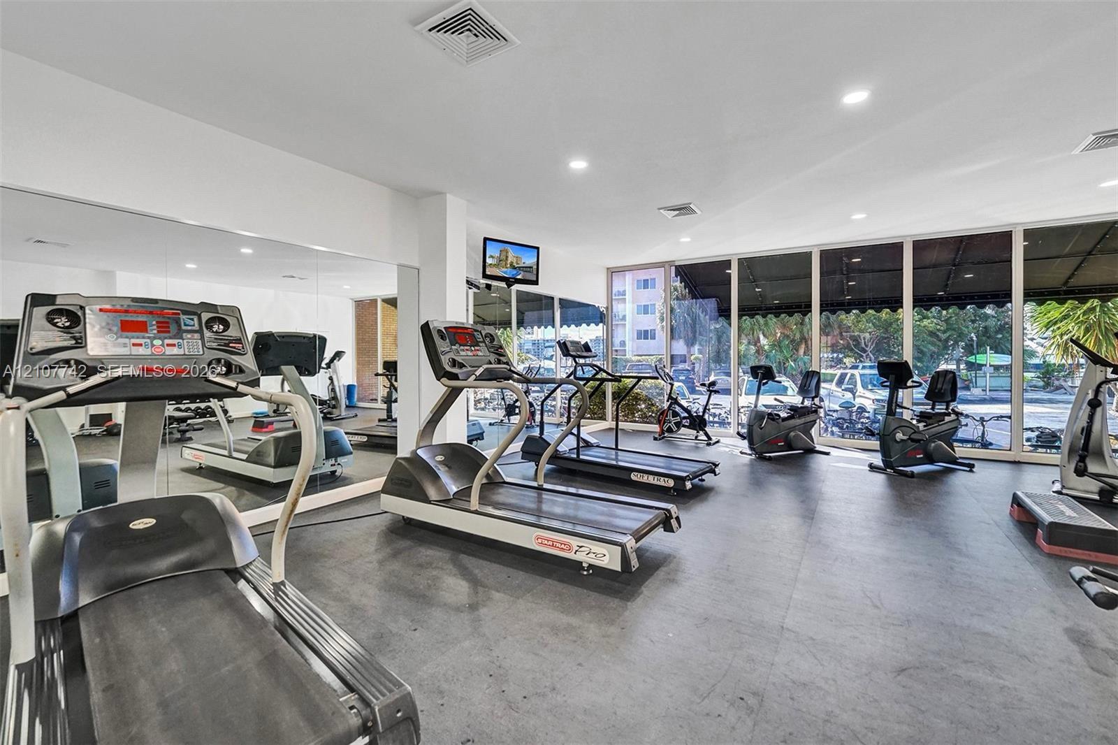 Fitness center featuring wall-to-wall mirrors, floor-to-ceiling glass windows, and durable rubberized flooring
