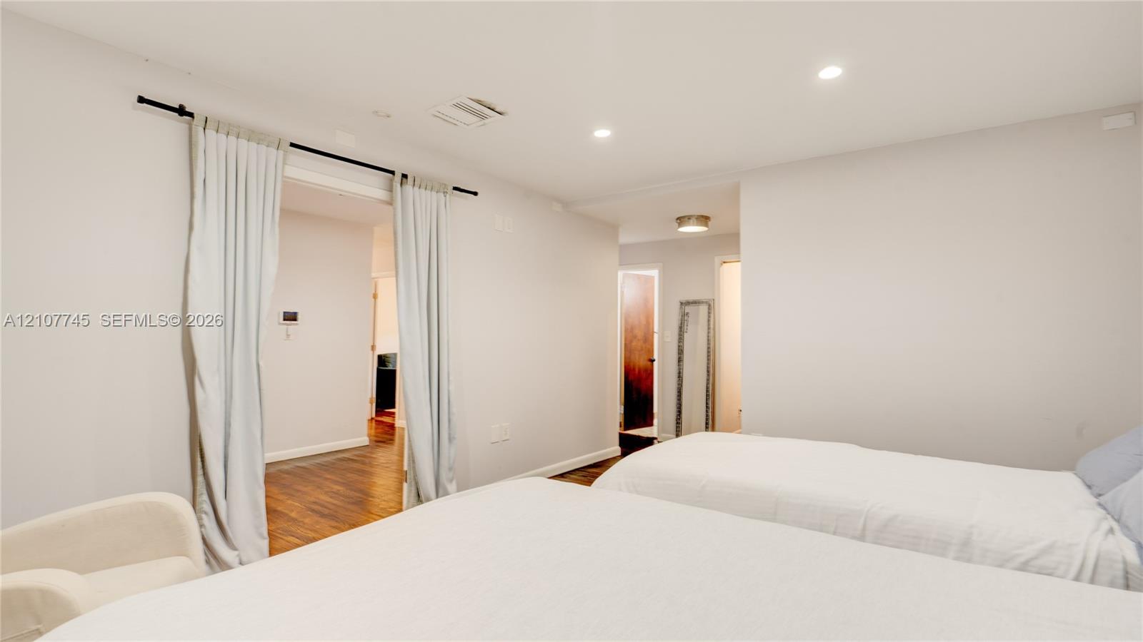 Neutral interior space featuring recessed ceiling lighting, wood-finish flooring, and a sliding curtain partition