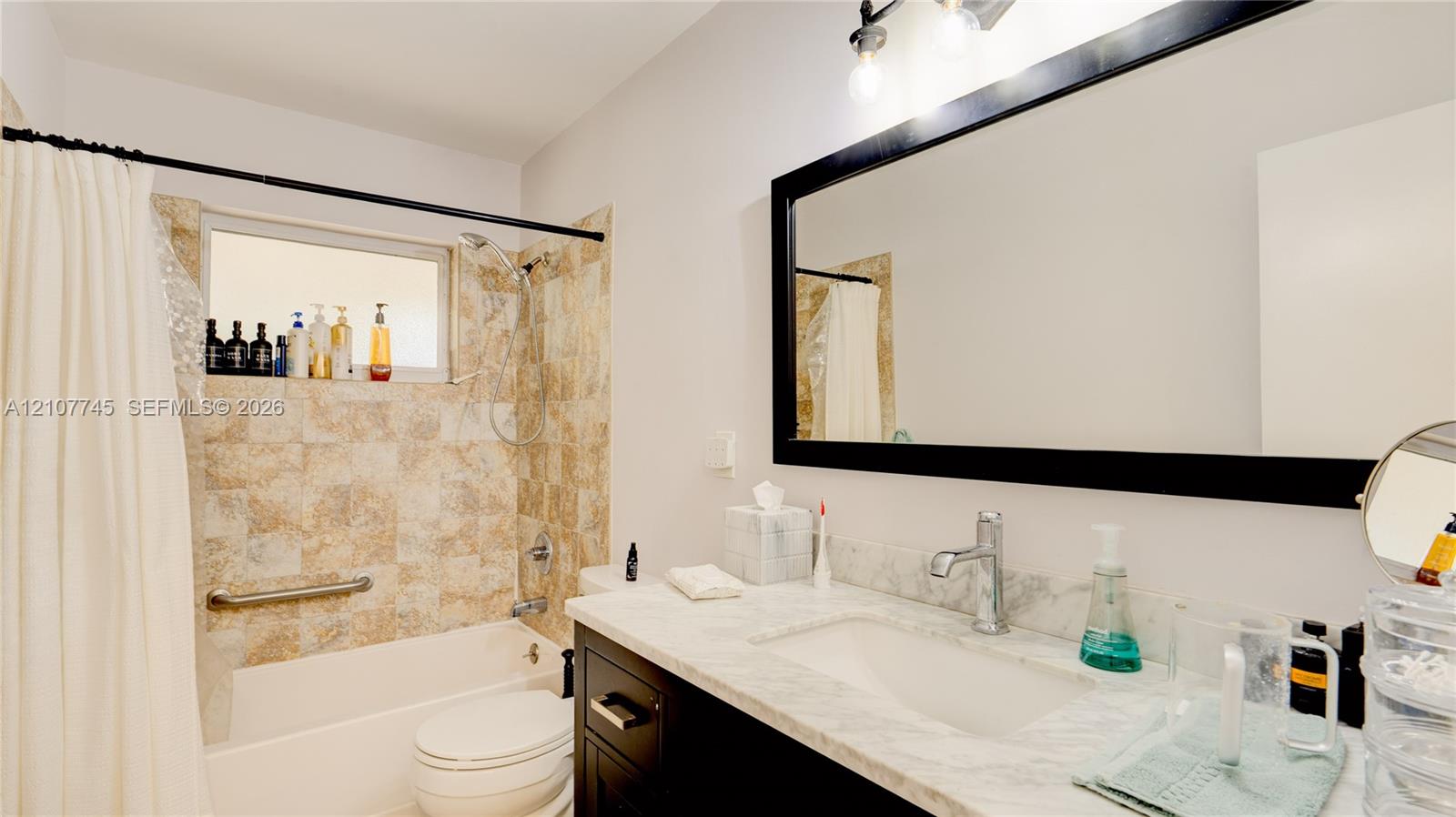 Bathroom featuring a vanity with a light-toned stone countertop, integrated sink, and dark cabinetry