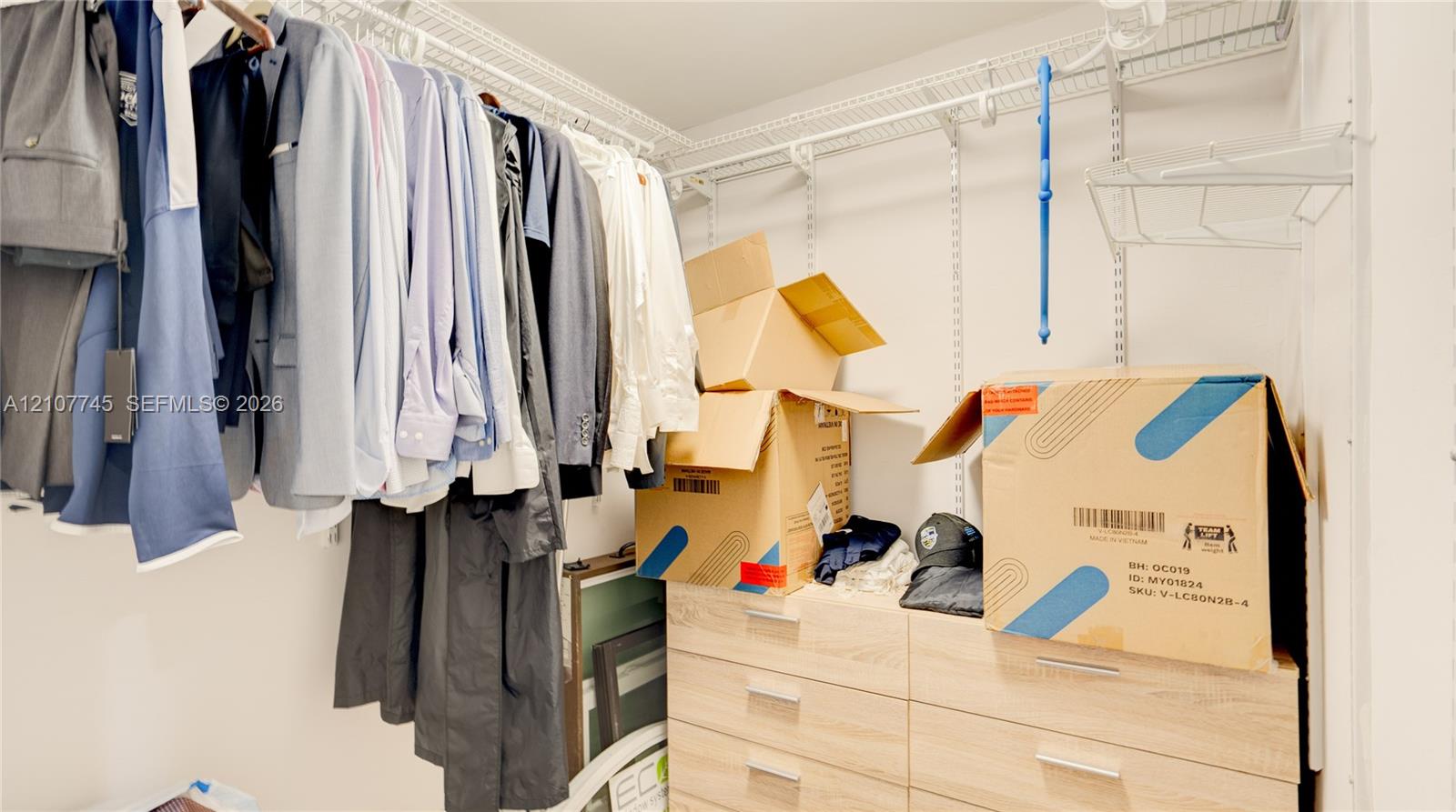 Walk-in closet featuring white wire shelving and built-in light-tone wood-finish drawer cabinetry