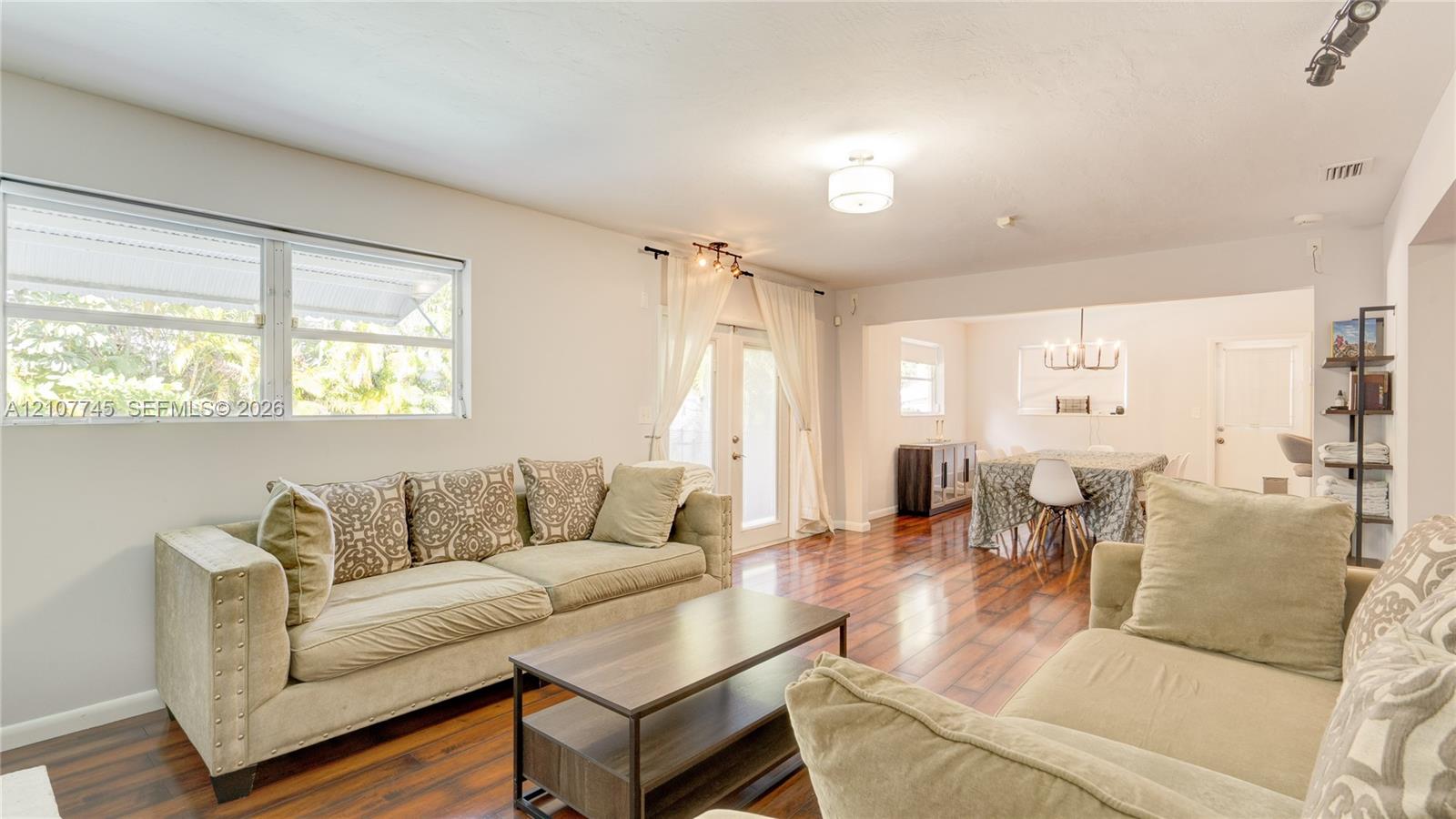 Open-concept interior featuring wood-finish flooring, dual-pane horizontal windows, recessed lighting, and glass-paned doors