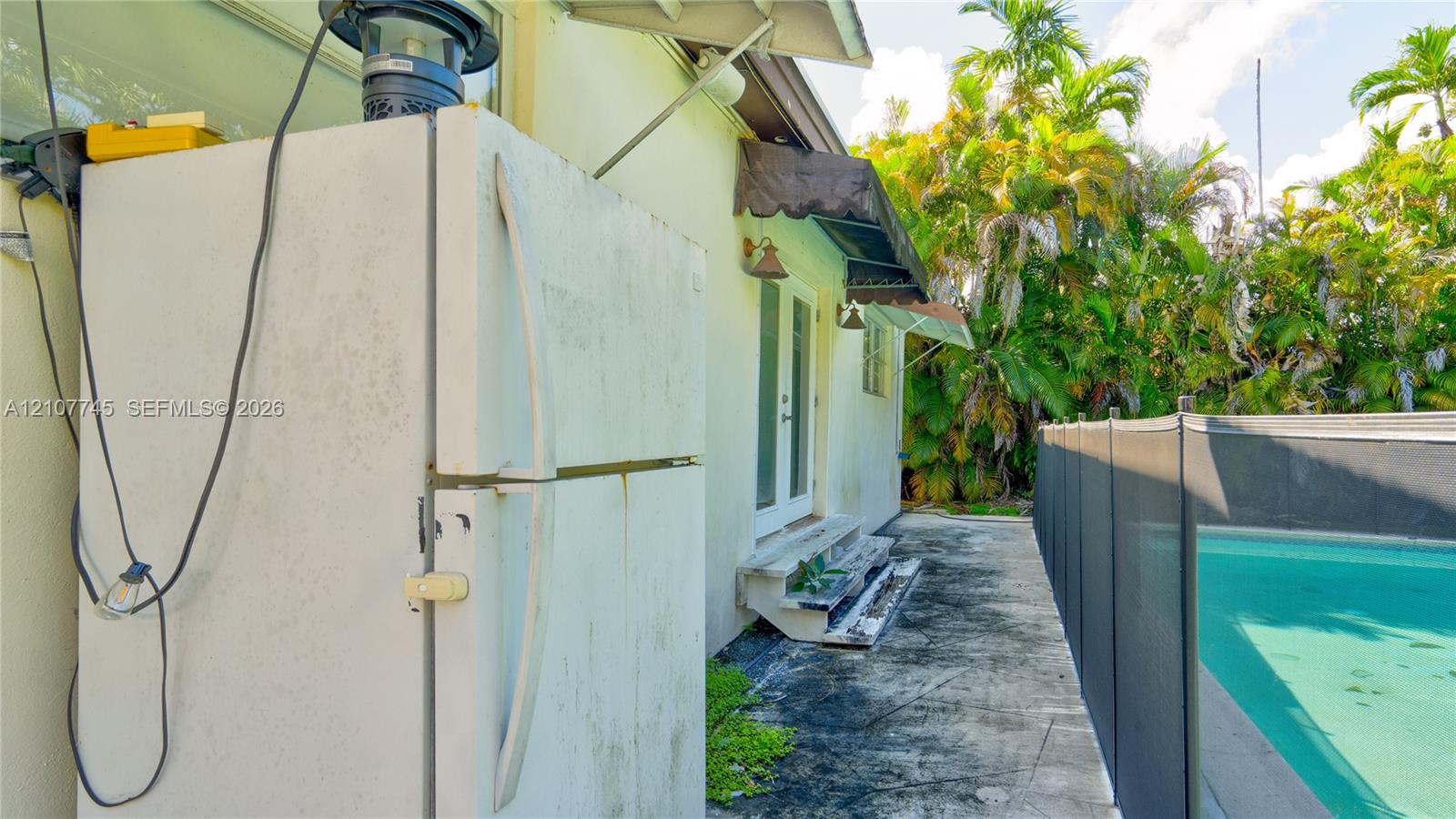 Exterior space featuring a concrete patio, a mesh safety pool fence, and a sliding glass door with a metal awning