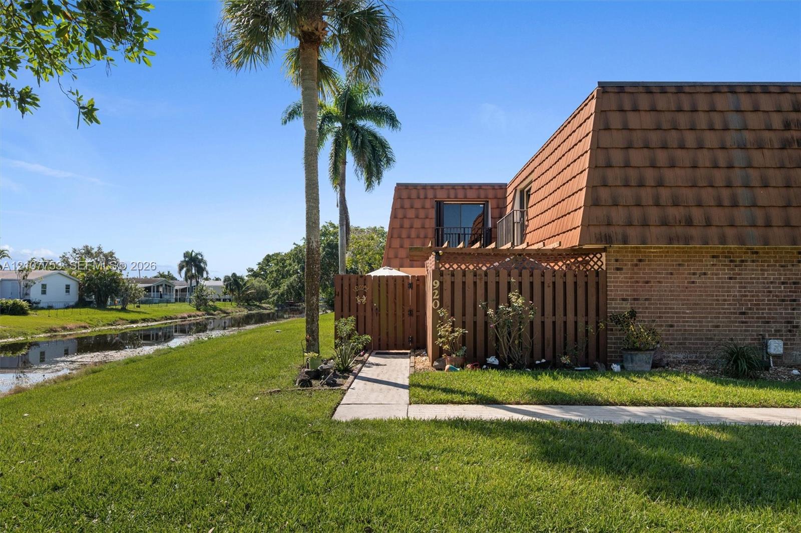 Exterior featuring a brick facade, shingle-style roofline, and wood-lattice privacy fencing with a gated entry