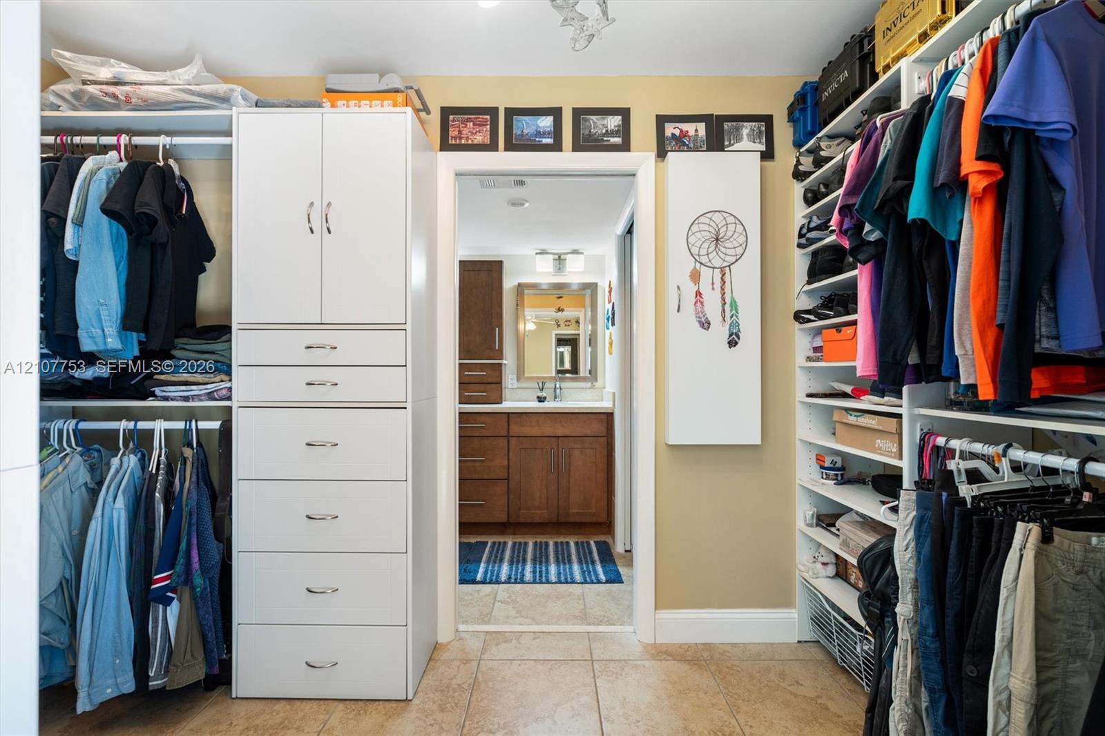 Walk-in closet featuring white custom cabinetry, integrated shelving, and tiled flooring