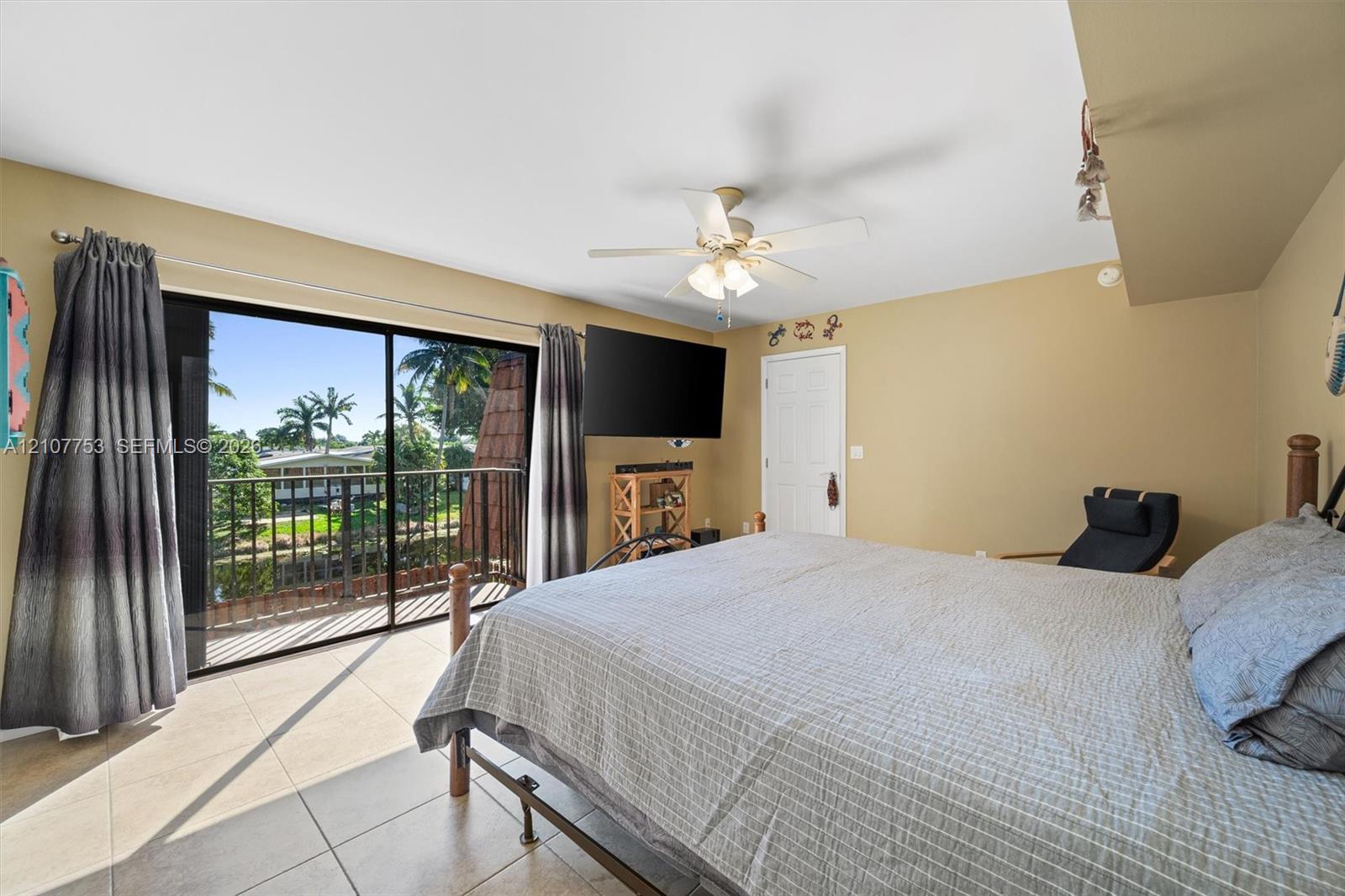 Sliding glass doors leading to a private balcony, ceramic tile flooring, and a ceiling fan with integrated lighting