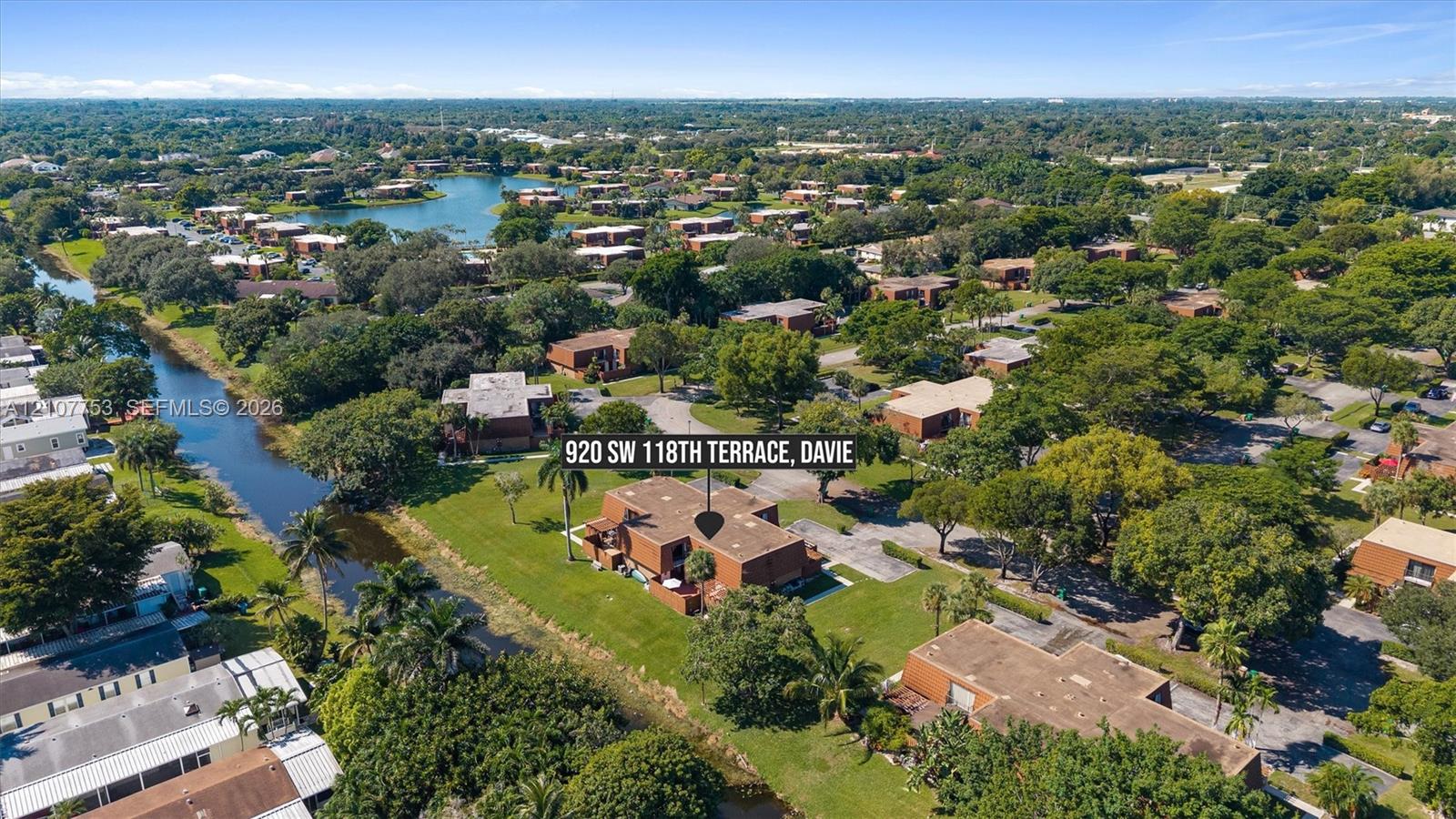 Aerial perspective of multi-story masonry residential building featuring expansive landscaped grounds, mature trees, and direct canal frontage