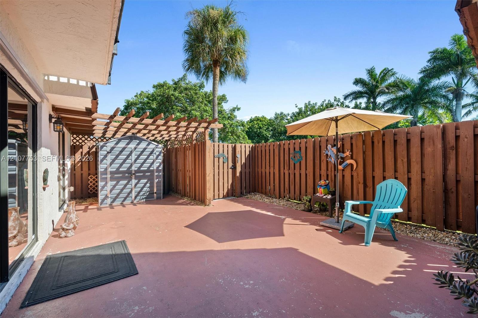 Paved patio featuring a wooden pergola, privacy fencing, and a detached storage structure