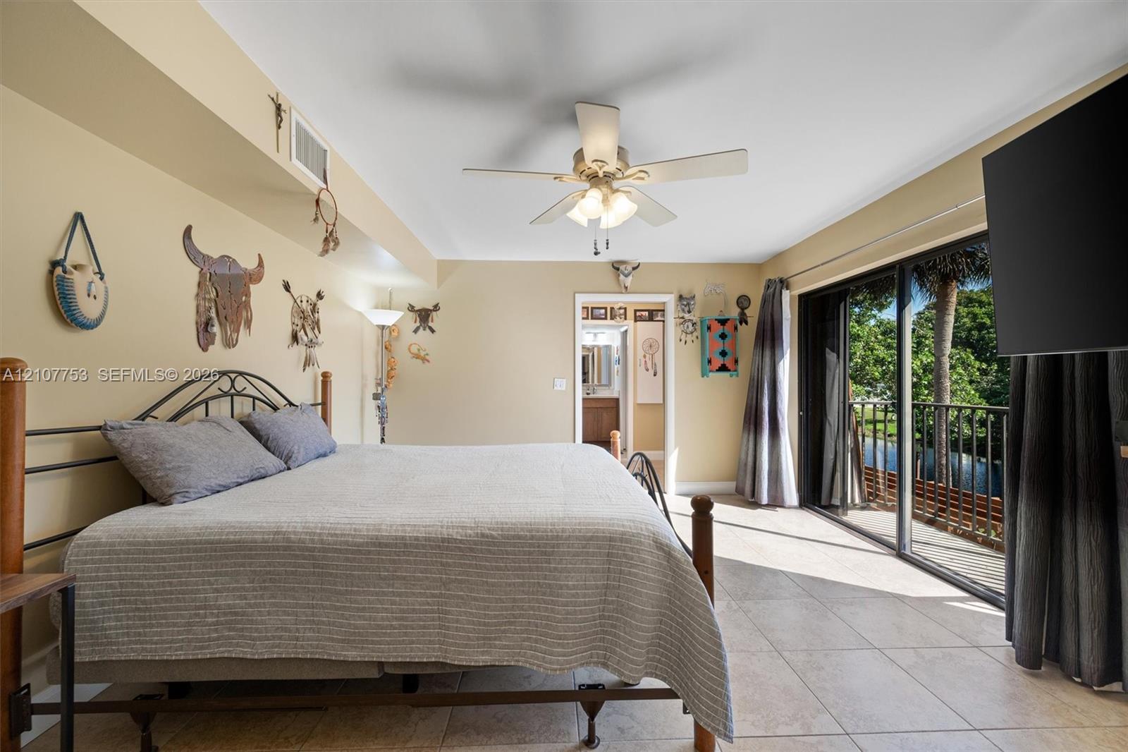 Ceramic tile flooring, ceiling fan with integrated lighting, and expansive sliding glass doors opening to an exterior balcony