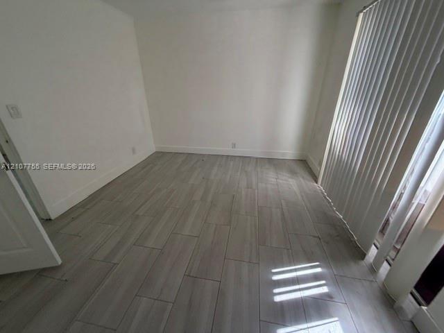 Neutral-toned interior room featuring wood-finish tile flooring and vertical window blinds
