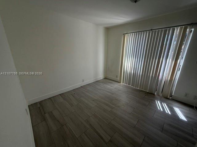 Interior room featuring wood-finish flooring and sliding glass doors with vertical blinds