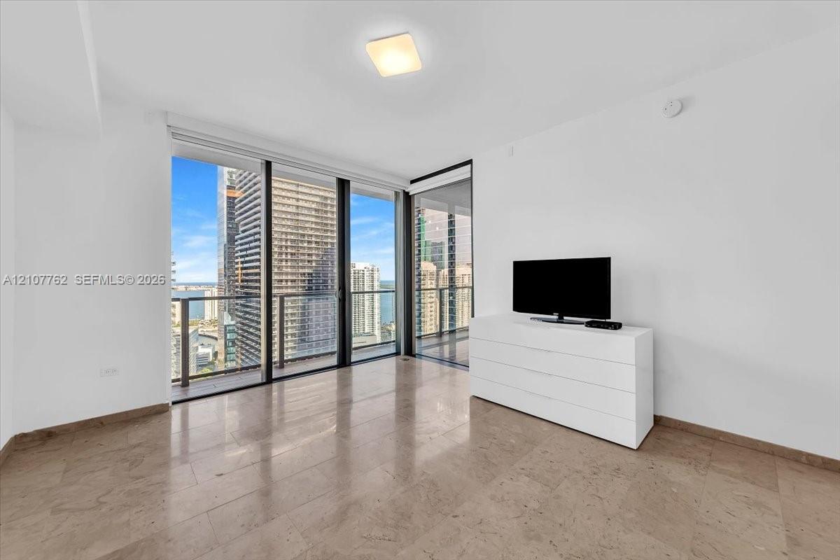 Floor-to-ceiling glass wall, polished stone flooring, and integrated balcony access