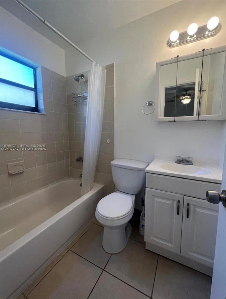 Bathroom featuring tiled shower surround, built-in vanity with cabinetry, integrated sink, mirrored medicine cabinet, and floor tile