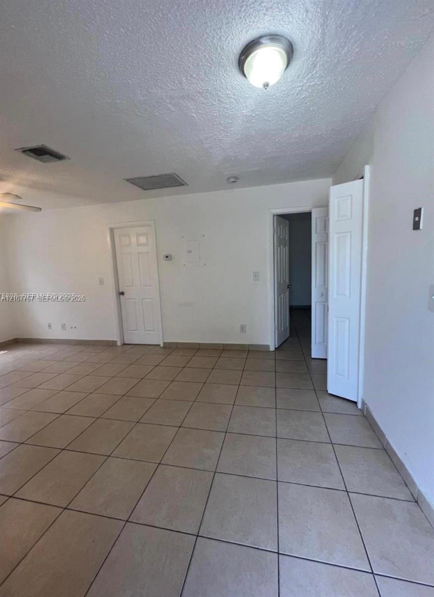 Neutral-toned ceramic tile flooring, solid-core interior doors, and overhead flush-mount lighting