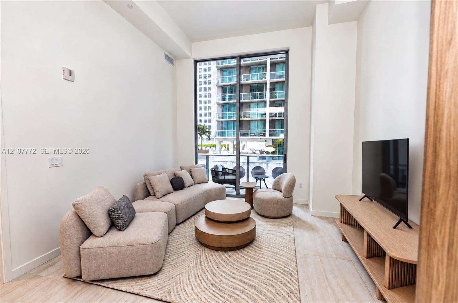 Floor-to-ceiling windows, sliding glass door access to balcony, neutral wall finish, and light-toned hard-surface flooring