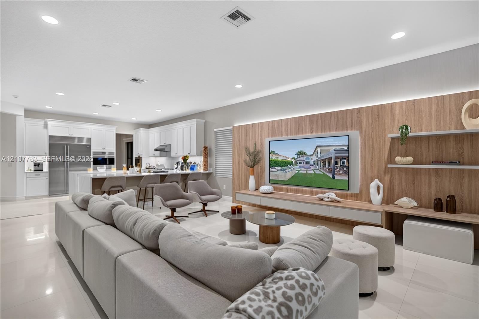 Open-concept area featuring polished tile flooring, recessed lighting, and a kitchen with white cabinetry and stainless steel appliances