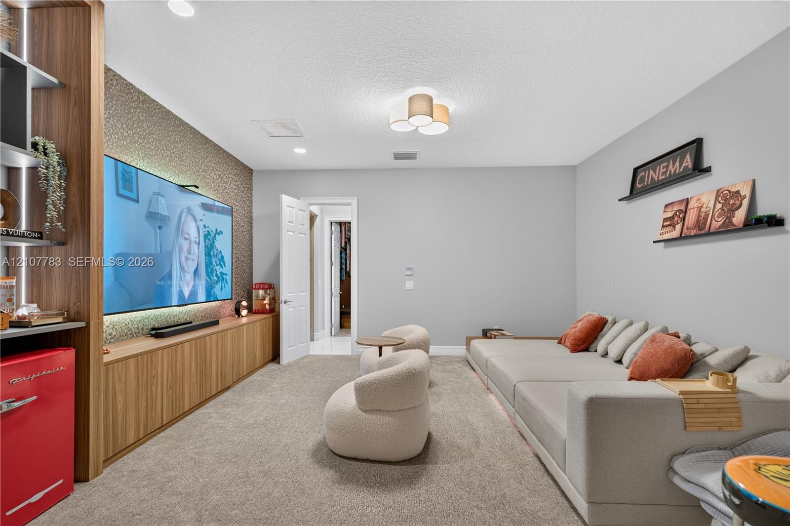 Custom built-in wood-finish cabinetry, textured accent wall, integrated recessed lighting, and flush-mount multi-bulb fixture