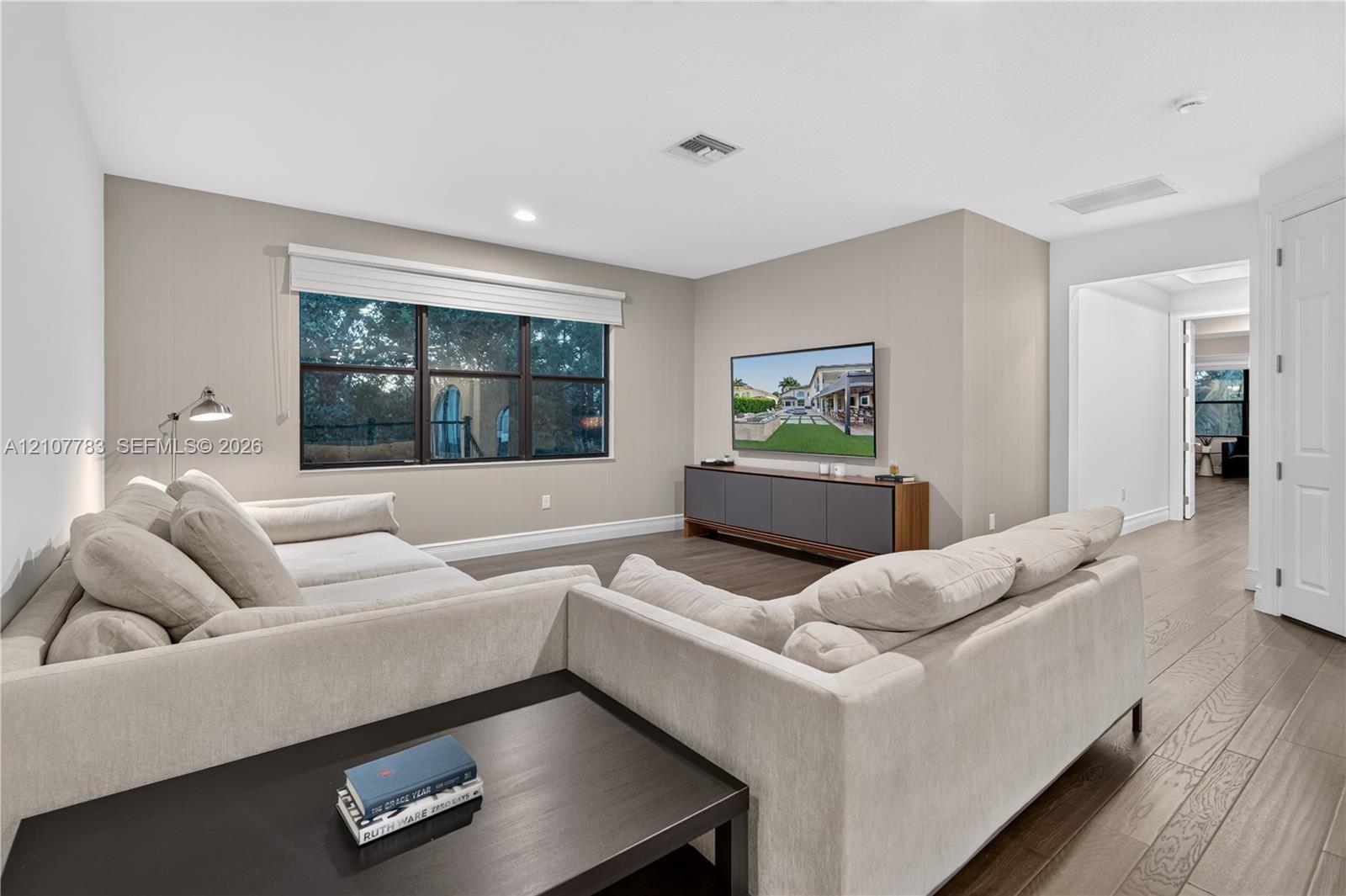 Neutral-toned interior featuring wood-finish flooring, multi-pane windows, recessed lighting, and a wall-mounted swing-arm lamp